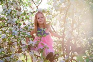 adorable petite fille appréciant le printemps dans le jardin en fleurs de pomme photo