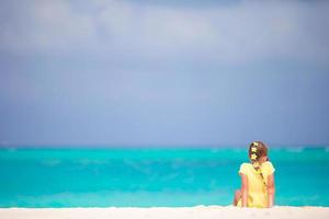 adorable petite fille avec des fleurs de frangipanier dans les cheveux sur la plage photo