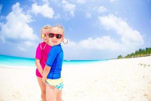 petites filles s'amusant sur une plage tropicale jouant ensemble en eau peu profonde photo