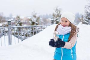 adorable petite fille tenant une lanterne de noël à l'extérieur par une belle journée de neige d'hiver photo