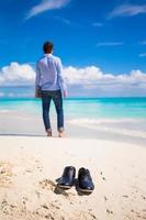 jeune homme avec ordinateur portable pendant les vacances à la plage tropicale photo