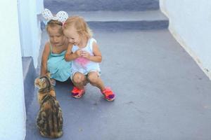 petites filles adorables assises près d'un chat dans un village grec, emporio, santorin photo