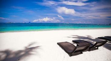 chaises de plage en bois pour les vacances et se détendre sur la plage de sable blanc tropical photo