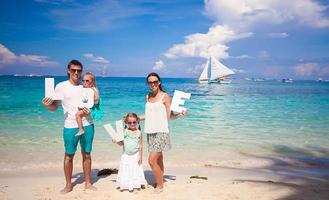 jeune famille heureuse et deux enfants avec mot amour en vacances tropicales photo