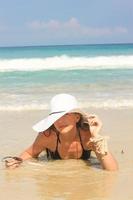 jeune femme sur la plage tenant un chapeau profitant des vacances d'été photo
