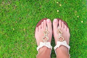 gros plan de tongs lumineuses et de jambes sur l'herbe verte photo