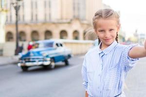 adorable petite fille prenant selfie dans un quartier populaire de la vieille havane, cuba. portrait d'enfant à l'extérieur dans une rue de la havane photo