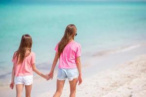 les petites filles drôles et heureuses s'amusent beaucoup sur la plage tropicale en jouant ensemble. photo