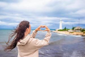 femme marche jusqu'au phare et fait du coeur photo