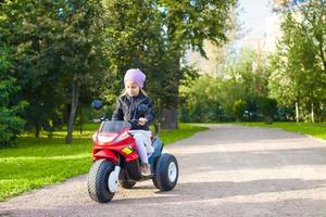 petite fille adorable sur son vélo dans un parc verdoyant photo