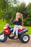adorable petite fille s'amusant sur sa moto jouet photo