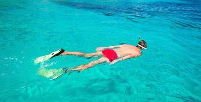 jeune homme plongée en apnée dans des eaux turquoises tropicales claires photo