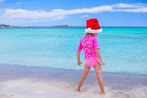 petite fille adorable en bonnet rouge sur la plage tropicale photo