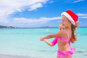 petites filles adorables en chapeaux de père noël pendant les vacances à la plage photo