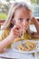 adorable petite fille mangeant des spaghettis dans un restaurant en plein air photo