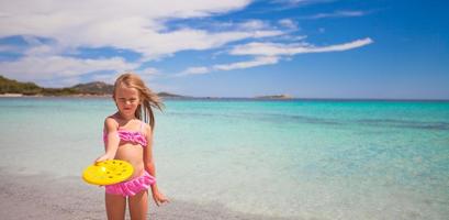 petite fille jouant au frisbee pendant des vacances tropicales dans la mer photo