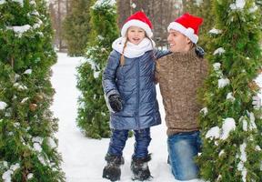 adorable petite fille et papa heureux en chapeaux de père noël à l'extérieur photo