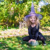 adorable petite fille en costume de sorcière jette un sort sur halloween photo