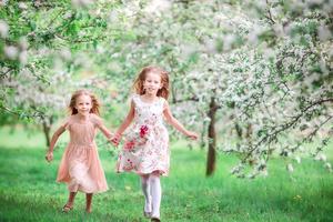 adorables petites filles dans un jardin de cerisiers en fleurs le jour du printemps photo