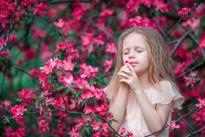 adorable petite fille appréciant l'odeur dans un jardin de printemps fleuri photo