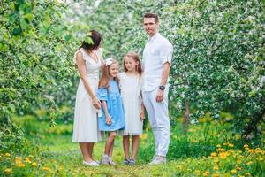 adorable famille dans un jardin de cerisiers en fleurs le beau jour du printemps photo