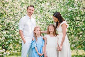 adorable famille dans un jardin de cerisiers en fleurs le beau jour du printemps photo