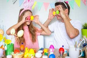 père et sa petite fille peignant des œufs. famille heureuse se préparant pour pâques. photo
