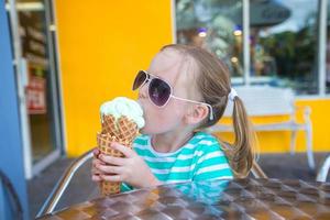petite fille mangeant de la glace dans un café en plein air photo