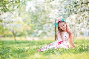 adorable petite fille dans un jardin de cerisiers en fleurs le jour du printemps photo