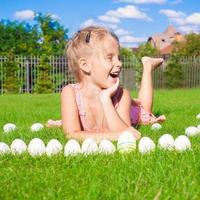 petite fille heureuse et drôle jouant avec des oeufs de pâques sur l'herbe verte photo
