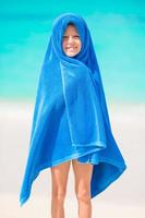 adorable petite fille enveloppée dans une serviette sur une plage tropicale après avoir nagé dans la mer photo