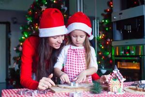 petite fille adorable et jeune mère préparant des biscuits de pain d'épice de noël photo