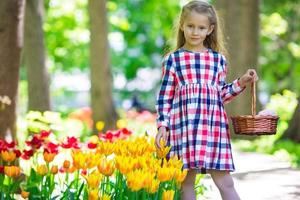 petite belle fille dans le jardin de tulipes au printemps chaud photo