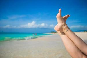 gros plan de pieds féminins sur une plage de sable blanc photo