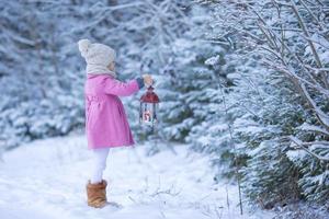 adorable petite fille avec lampe de poche sur noël à l'extérieur de la forêt d'hiver photo