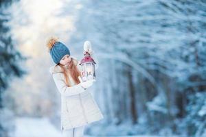 adorable petite fille avec lampe de poche sur noël à l'extérieur de la forêt d'hiver photo