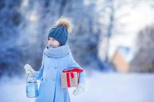 adorable fille avec cadeau de boîte de noël en hiver à l'extérieur la veille de noël photo