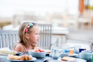 adorable petite fille prenant son petit déjeuner au café en plein air photo