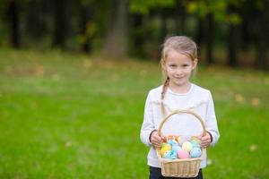 adorable petite fille tenant un panier avec des oeufs de pâques le jour du printemps à l'extérieur photo