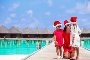 jeune mère et petites filles en bonnet de noel pendant les vacances de noël photo