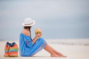 jeune femme buvant du lait de coco sur la plage photo