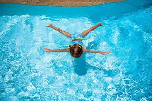 petite fille mignonne et heureuse nage dans la piscine photo