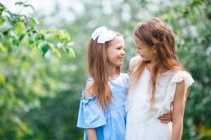 adorables petites filles dans un jardin de pommiers en fleurs le jour du printemps photo