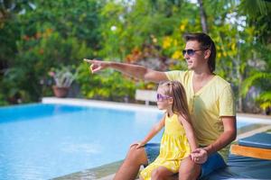 petite fille avec son père s'amuse près de la piscine d'un complexe exotique photo