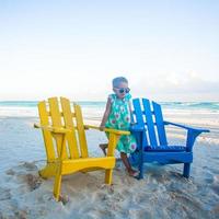 petite fille dans des chaises colorées en bois de plage sur la plage tropicale de tulum, mexique photo