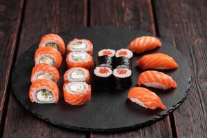 ensemble de sushis du haut sur fond noir en gros plan. un assortiment de divers maki nigiri et rolls sauce soja aux fruits de mer