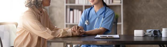 un patient heureux tient le soignant pour une main tout en passant du temps ensemble. femme âgée dans une maison de retraite et infirmière photo