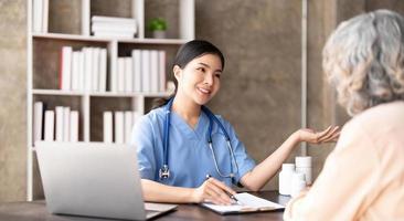 une patiente âgée âgée asiatique consulte une infirmière médecin dans une maison de soins infirmiers. soignant thérapeute pharmacien fille tenir une bouteille de pilules de médecine, expliquer la prescription à un homme handicapé plus âgé photo