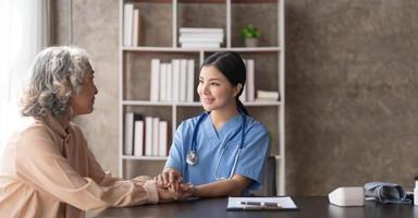 un patient heureux tient le soignant pour une main tout en passant du temps ensemble. femme âgée dans une maison de retraite et infirmière photo