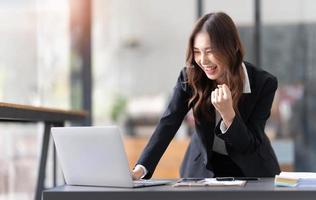 belle femme asiatique utilisant un ordinateur portable, excitante et célébrant avec de bonnes nouvelles d'affaires réussies. concept de démarrage de petite entreprise. photo